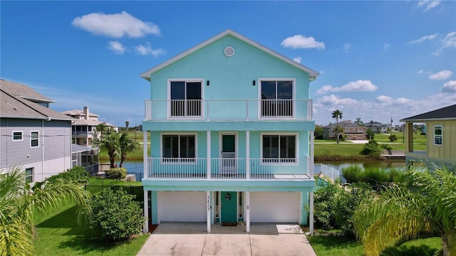 raised beach house with a water view, a balcony, and a garage