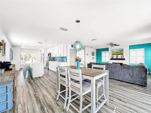 dining space featuring ceiling fan, light hardwood / wood-style floors, and sink