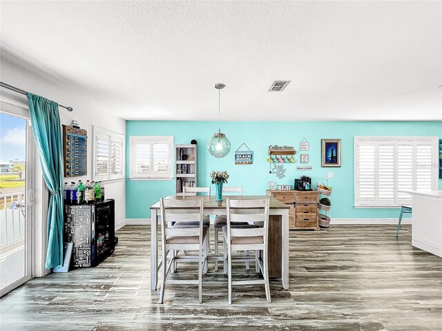 interior space featuring hanging light fixtures, hardwood / wood-style flooring, a breakfast bar, and a textured ceiling