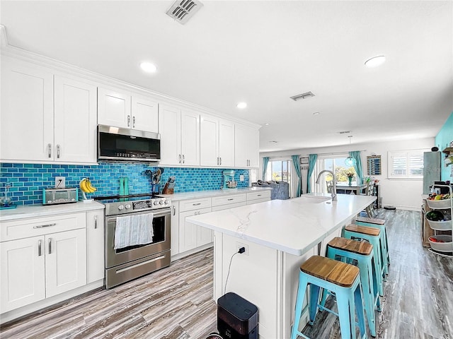 kitchen with stainless steel appliances, a breakfast bar area, and white cabinets