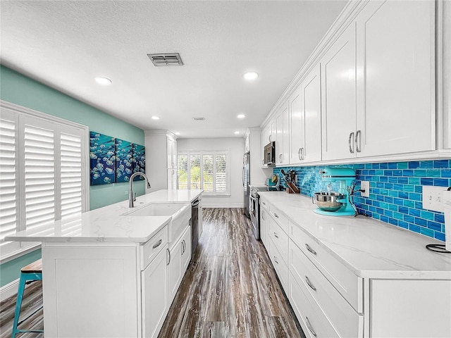 kitchen with sink, light stone counters, dark hardwood / wood-style flooring, stainless steel appliances, and white cabinets