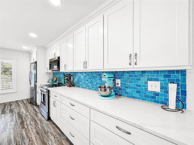 kitchen featuring white cabinetry, stainless steel appliances, light stone countertops, dark hardwood / wood-style flooring, and decorative backsplash