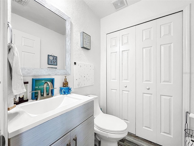 bathroom with vanity, toilet, wood-type flooring, and a textured ceiling