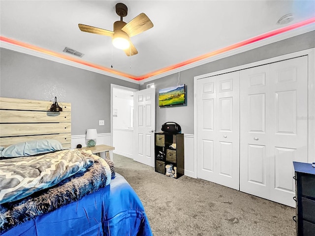 carpeted bedroom featuring ceiling fan, ornamental molding, and a closet