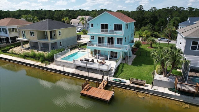 back of house with a water view, a balcony, a yard, and a patio area