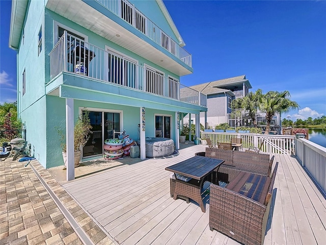 wooden terrace featuring a hot tub and a water view