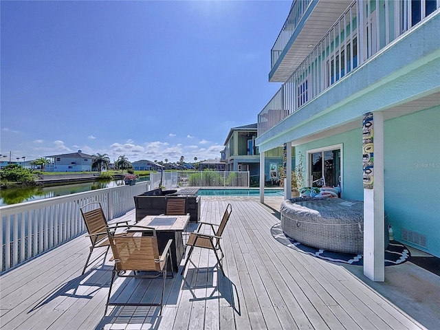 wooden deck featuring a water view and a fenced in pool