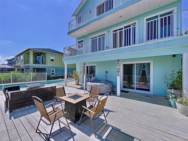 wooden deck featuring a pool with hot tub and an outdoor fire pit