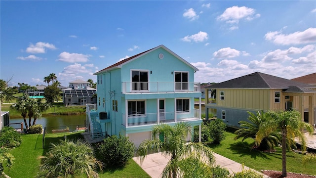 back of property featuring a water view, a balcony, a garage, and a yard