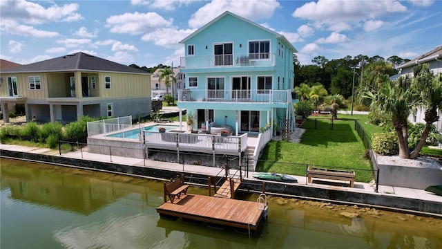 back of house with a patio area, a lawn, a balcony, and a water view