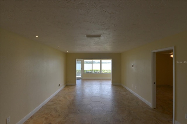 tiled empty room featuring a textured ceiling