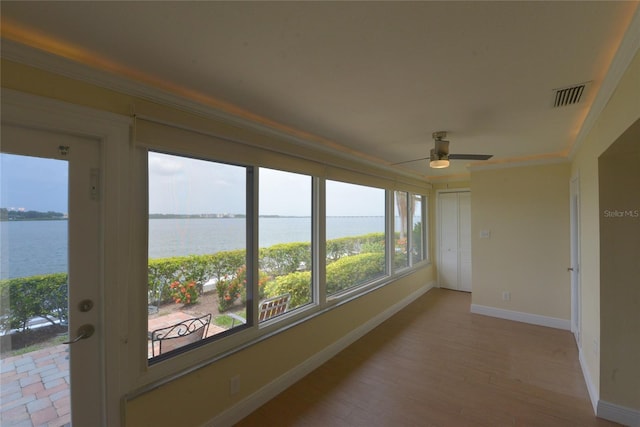 unfurnished sunroom with a water view, ceiling fan, and a healthy amount of sunlight