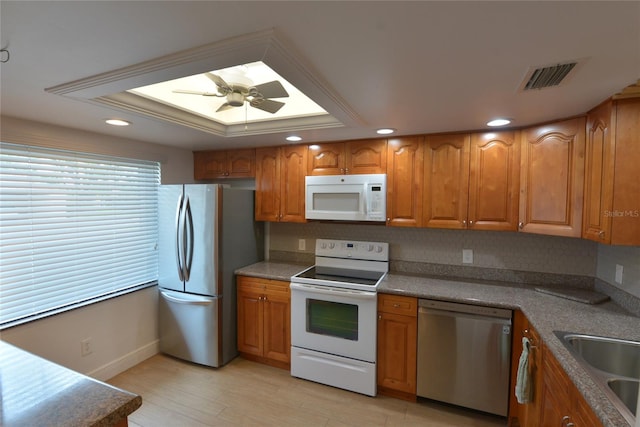 kitchen featuring tasteful backsplash, light wood-type flooring, ceiling fan, appliances with stainless steel finishes, and a raised ceiling