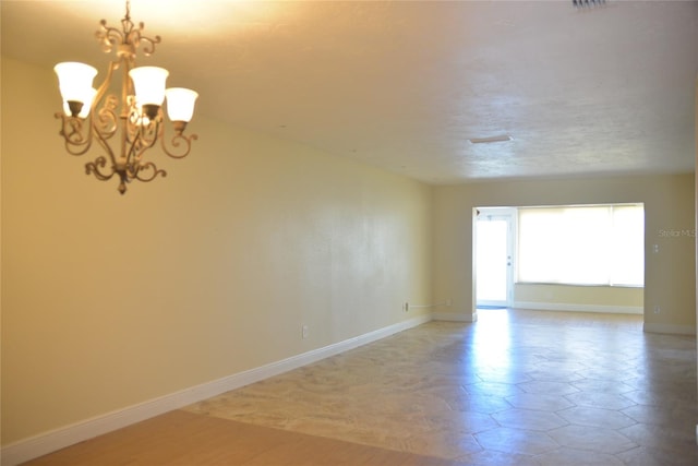 empty room with tile patterned floors and an inviting chandelier