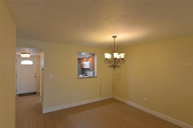 spare room with hardwood / wood-style floors and an inviting chandelier