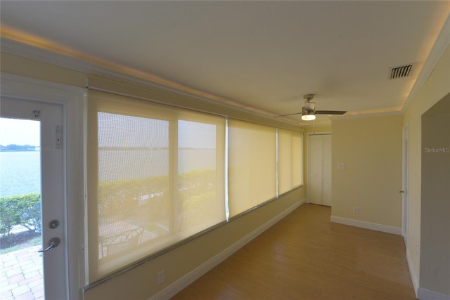 unfurnished sunroom with a water view and ceiling fan