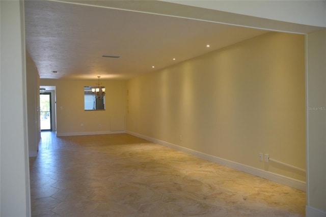 empty room with tile patterned flooring and a chandelier