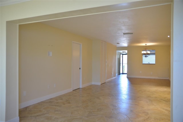 empty room with tile patterned floors and a notable chandelier