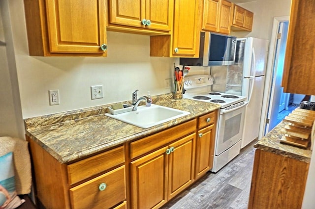 kitchen with light stone counters, white appliances, sink, and hardwood / wood-style floors