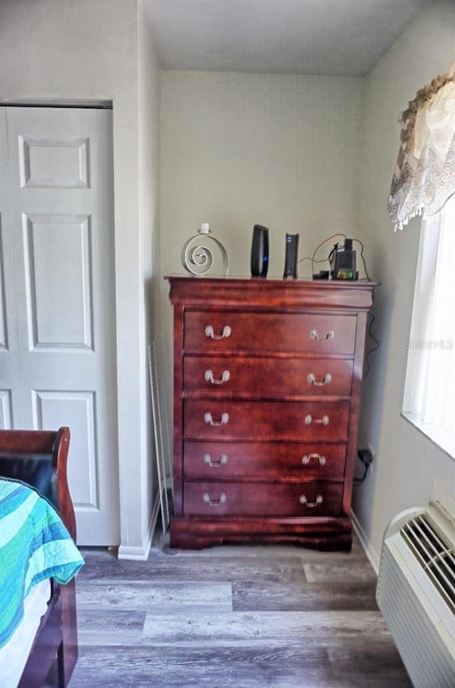 bedroom with wood-type flooring and an AC wall unit