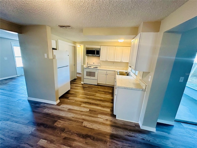 kitchen featuring white appliances, a textured ceiling, white cabinets, wood-type flooring, and sink