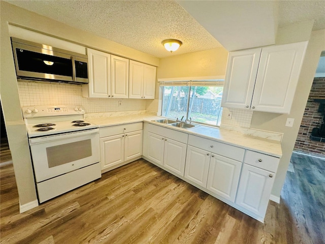 kitchen with white cabinetry, light wood-type flooring, and white range with electric stovetop