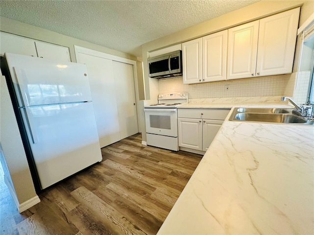 kitchen with white cabinetry, white appliances, decorative backsplash, wood-type flooring, and sink