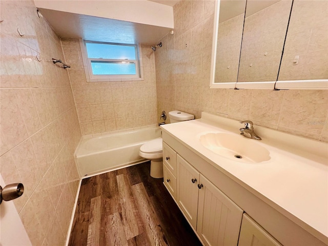 full bathroom featuring tile walls, toilet, vanity, tiled shower / bath combo, and wood-type flooring