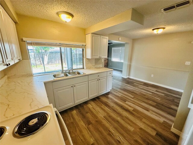 kitchen with range, sink, a textured ceiling, white cabinetry, and wood-type flooring