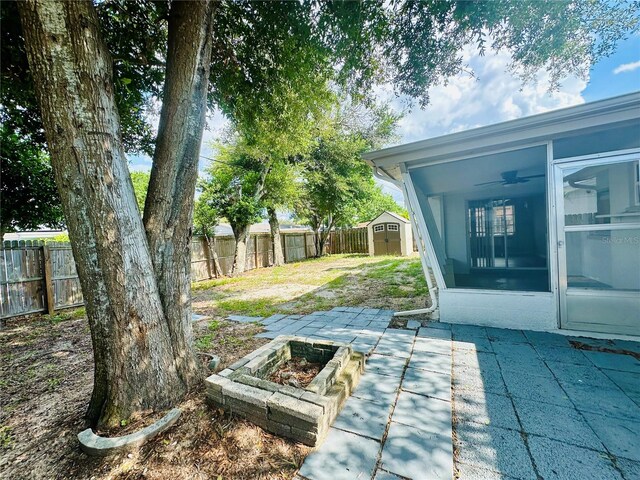 view of yard featuring a sunroom, a patio, and a storage unit