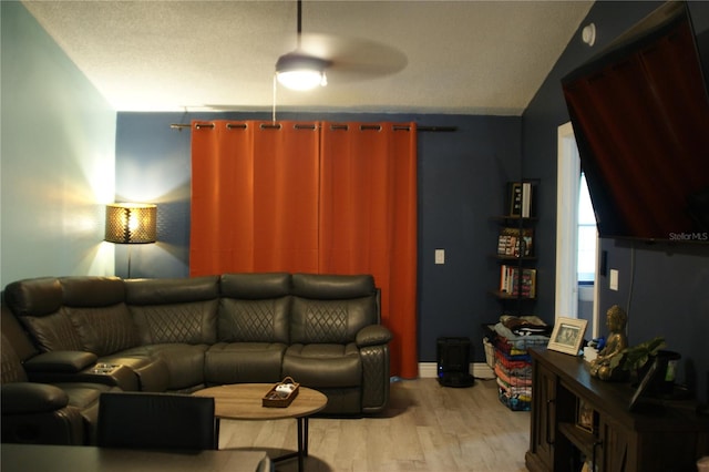 living room with lofted ceiling, a textured ceiling, light wood-type flooring, and ceiling fan