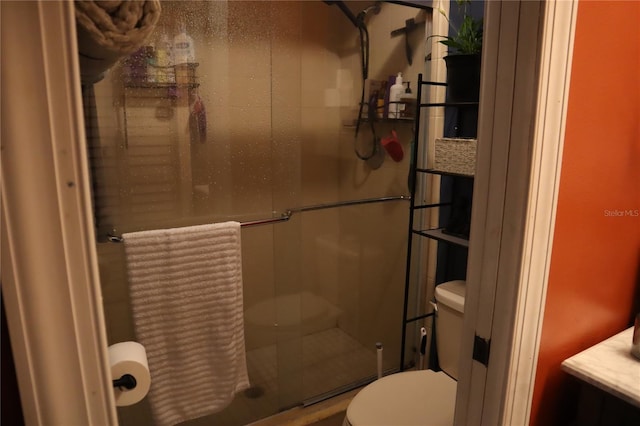 bathroom with a shower with shower door and toilet