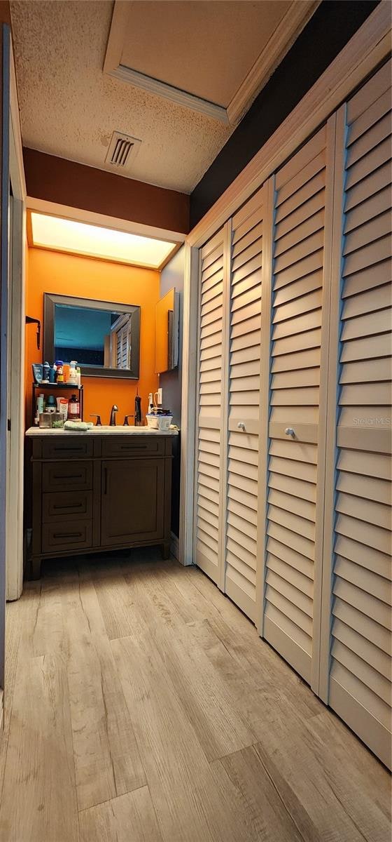 exterior space featuring sink, light wood-type flooring, and a textured ceiling