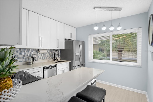 kitchen featuring stainless steel appliances, backsplash, white cabinets, sink, and a kitchen breakfast bar