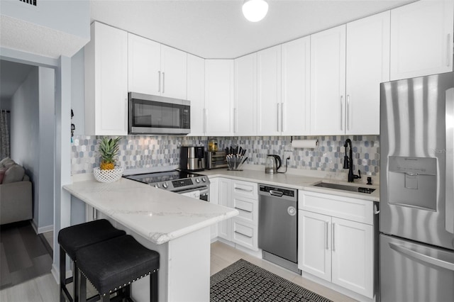 kitchen featuring a breakfast bar area, tasteful backsplash, light stone counters, stainless steel appliances, and sink