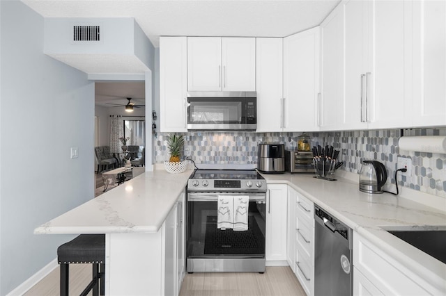 kitchen featuring a breakfast bar area, tasteful backsplash, appliances with stainless steel finishes, and ceiling fan