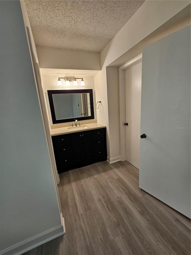 bathroom with hardwood / wood-style flooring, vanity, and a textured ceiling