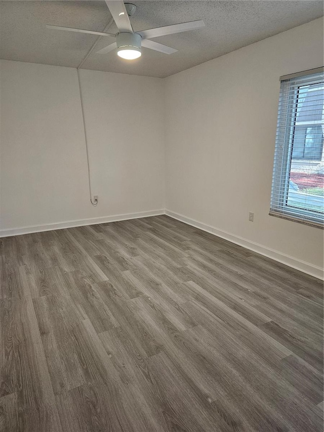 empty room featuring dark wood-type flooring, a textured ceiling, and ceiling fan