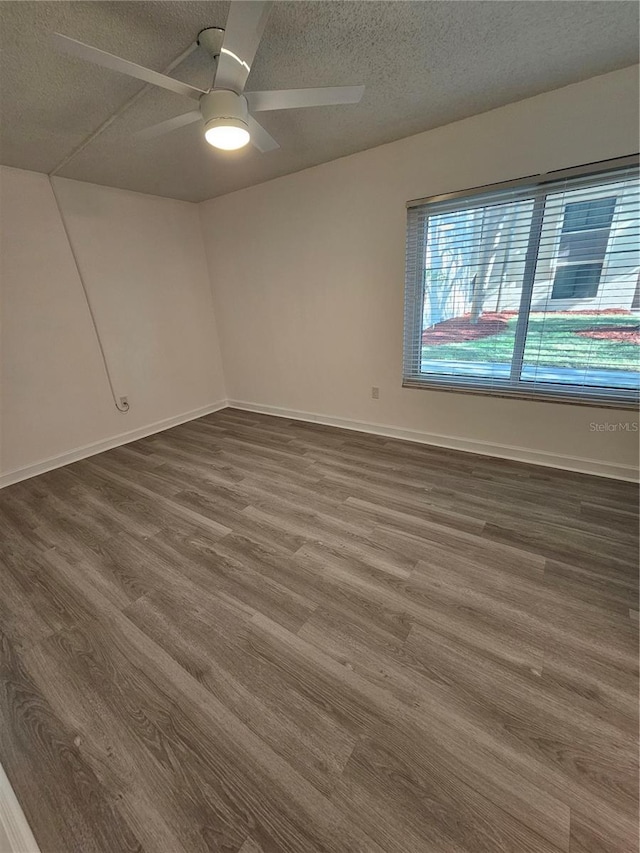 spare room with dark hardwood / wood-style floors, ceiling fan, and a textured ceiling