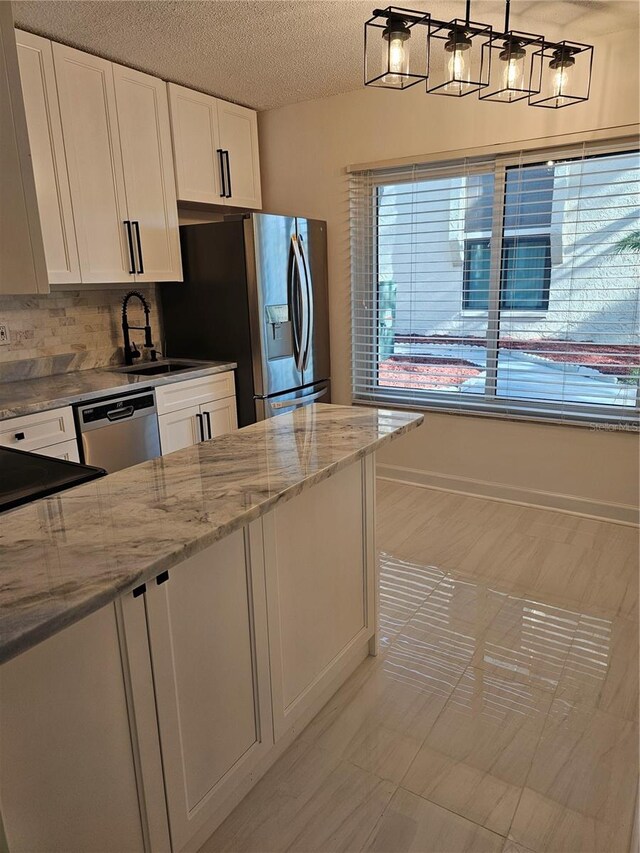 kitchen with stainless steel appliances, white cabinets, sink, light tile patterned floors, and light stone countertops