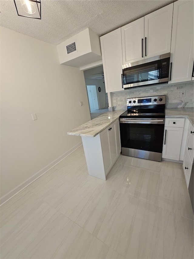 kitchen with tasteful backsplash, appliances with stainless steel finishes, light tile patterned floors, and kitchen peninsula