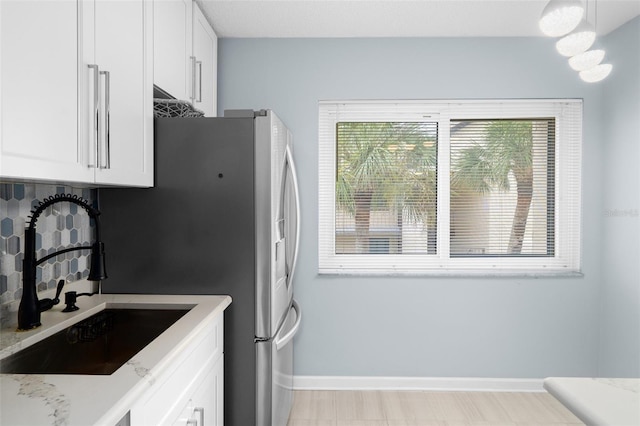 2207 Belleair Rd Unit A32, Clearwater, FL 33764 - kitchen featuring a sink, white cabinets, baseboards, and light stone counters