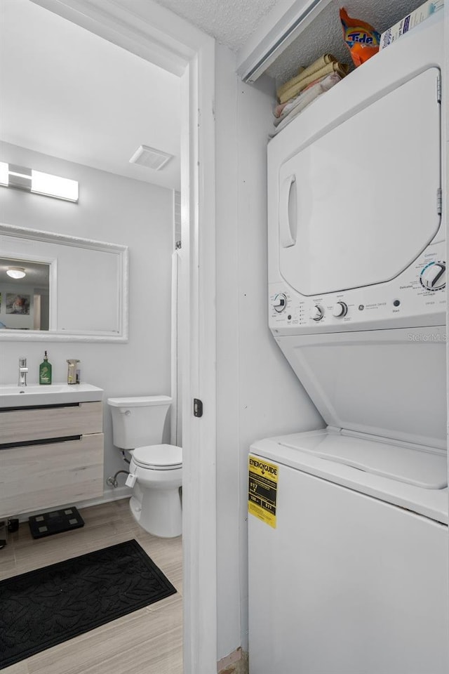 2207 Belleair Rd Unit A32, Clearwater, FL 33764 - bathroom featuring stacked washing machine and dryer, toilet, wood finished floors, and vanity