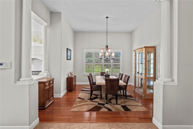 dining room featuring decorative columns, a chandelier, and light hardwood / wood-style floors