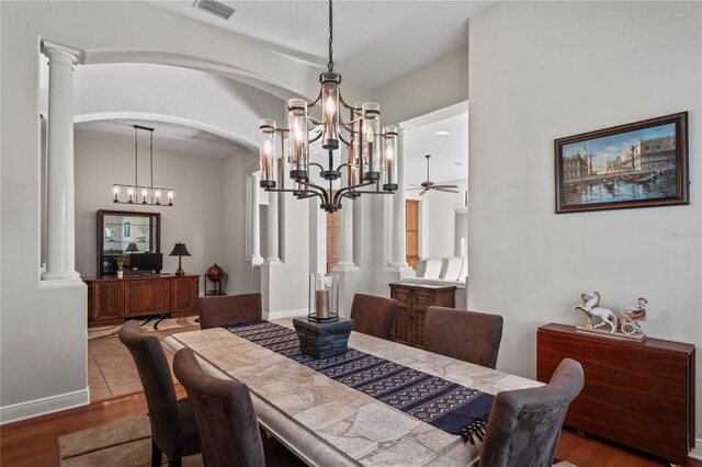 dining space featuring decorative columns, ceiling fan with notable chandelier, and hardwood / wood-style floors