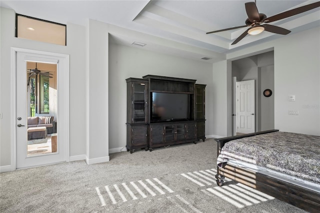 bedroom featuring a raised ceiling, light colored carpet, and ceiling fan