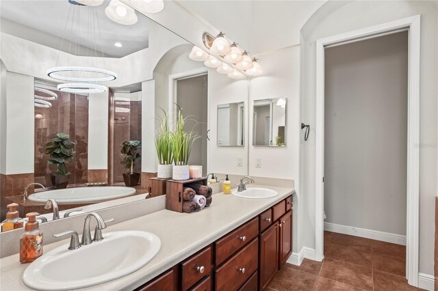 bathroom with dual vanity, tile patterned floors, and a tub to relax in