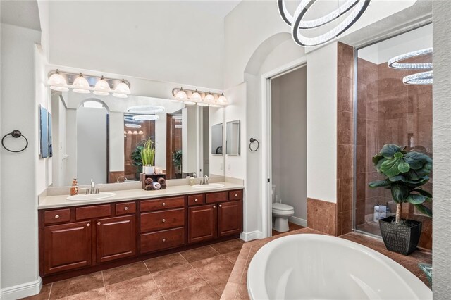 full bathroom featuring toilet, tile patterned floors, shower with separate bathtub, and dual bowl vanity