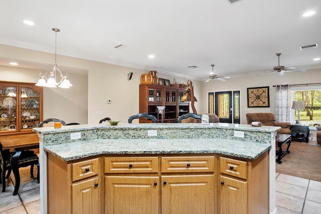 kitchen featuring light stone counters, hanging light fixtures, light tile patterned floors, and a center island