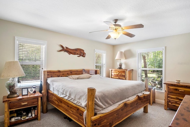 carpeted bedroom featuring ceiling fan, a textured ceiling, and multiple windows